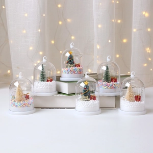 Close-up of Christmas miniature landscape with miniature tree and snow in glass dome