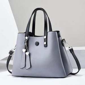 Sac à main gris pour femme avec anses noires et pendentif en cœur sur fond blanc