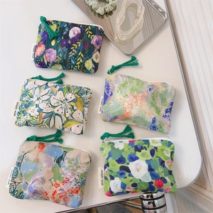 Flat lay of five oil painting style floral cotton pouches with fringe tassels and labels