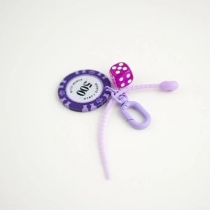 Purple poker chip keychain featuring a Monte Carlo 500 club design and a matching dice