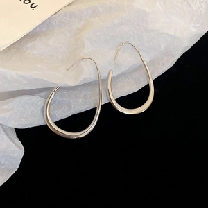 Macro shot of minimalist silver teardrop earrings on artistic contrast background