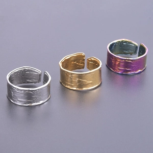Drei Edelstahlringe mit Rindenstruktur in Silber, Gold und Lila im Detail betrachtet