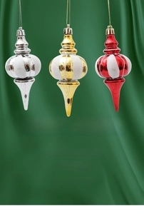Detailansicht roter, goldener und silberner Weihnachtshänger auf grünem Satin