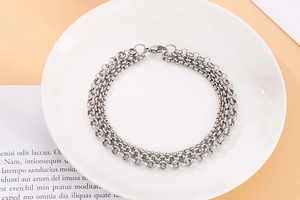 Detail view of silver stainless steel triple layer bracelet with pearl chain on a plate