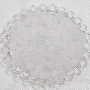Macro view of 6mm white frosted glass beads displayed in a decorative glass tray