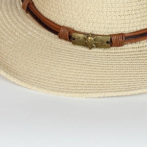 Close-up of beige straw hat with brown leather band and bronze skull metal buckle