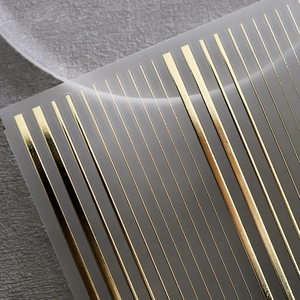 Glossy gold metallic parallel lines nail art stickers with 3D texture on dark stone background