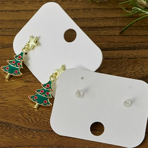 Golden Christmas tree earrings with green enamel and red dots on a wooden background