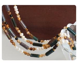 Detailed close-up of handmade necklace with natural stones and freshwater pearls