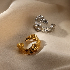 Detailed view of silver and gold irregular wavy open rings on beige silk fabric