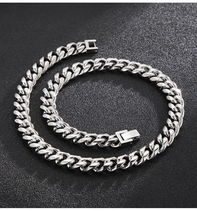 Macro detail of silver polished stainless steel Cuban link chain on dark textured background