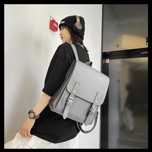 Side view of a vintage grey leather backpack worn by a model in a minimalist setting
