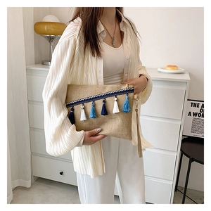 Detail of hand-woven envelope clutch featuring ethnic fringe tassels and blue webbing