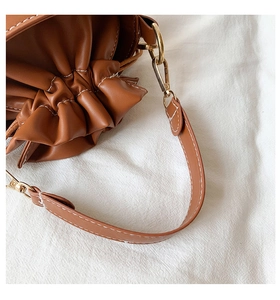 Detail of lychee pattern brown bucket bag with contrast white stitching and gold hardware