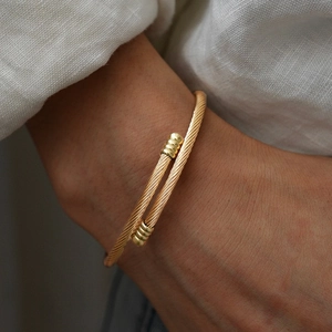 Macro view of golden cable twisted cuff bracelet with sphere ends on a model wrist