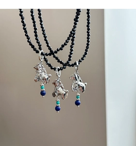 Macro shot of silver mythical beast pendant on black beaded necklaces with turquoise accents