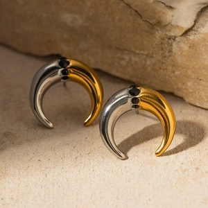 Macro detail of two-tone gold and silver C-hoop earrings with black gemstones on stone