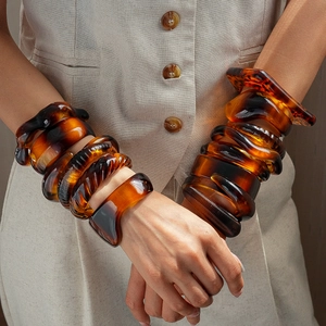 Close-up of stacked tortoiseshell resin bangles with irregular geometric shapes for women
