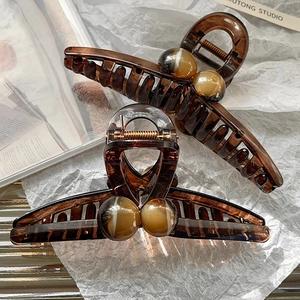 Detail of amber acrylic hair claw clip with marble texture beads on white art paper