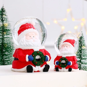 Macro shot of two Santa Claus snow globes with glowing Christmas tree bokeh background