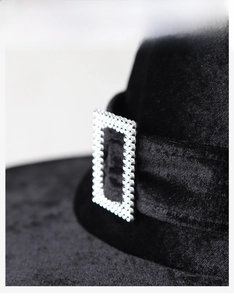 Detailed macro view of dense black velvet fabric with an elegant silver buckle on a hat