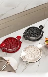 Manual meat shredders in red, black, and white on a marble kitchen countertop detail view