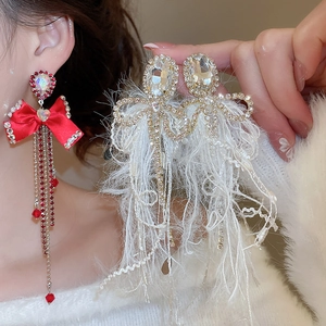 Detail of red bow earrings with long tassels and white feather rhinestone tassel earrings