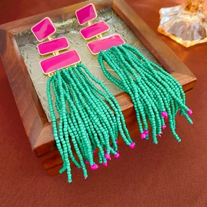 Detailed shot of long boho earrings with green seed bead tassels and pink rectangular studs