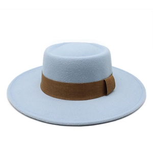 Detail of light blue wool felt boater hat with a wide brown ribbon on a white background