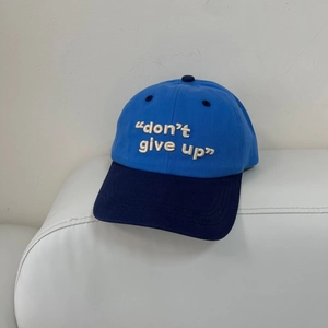 Detalle del texto bordado 'don't give up' en una gorra de béisbol azul bicolor