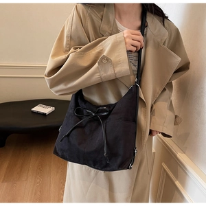 Chic black velvet tote bag with bow detail styled with a khaki trench coat and white tee