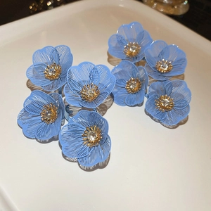 Détails de boucles d'oreilles fleurs en filigrane bleu avec cristaux et cœurs dorés