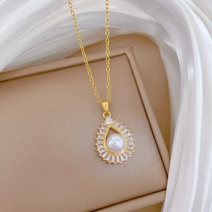 Detailed shot of golden teardrop necklace with pearl and rhinestones on a jewelry box