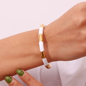 Detailed view of women's white enamel and gold-plated stainless steel bamboo texture bangle