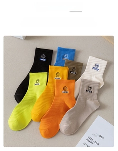 Detail of ribbed knit crew socks featuring embroidered smiley face patch and colorful assortment