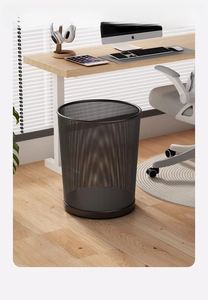 Detail of round black wire mesh trash bin with reinforced base on wood floor in a study room