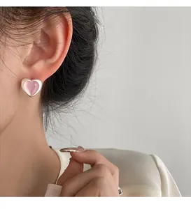 Close-up of pink heart-shaped earrings on model highlighting the elegant silver setting