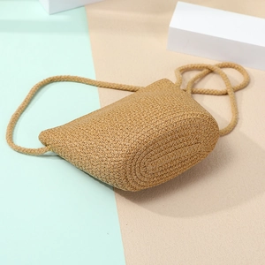 Close-up of handmade straw shell crossbody bag with detailed woven texture on two-tone background