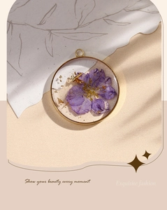 Macro shot of purple dried flowers and gold flakes in resin pendant necklace