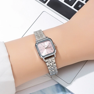 Detail view of a square pink dial watch with silver steel strap on a woman's wrist