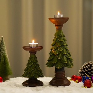 Set of two green resin Christmas tree candle holders on a snowy festive tabletop