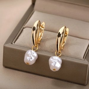 Macro shot of gold geometric earrings with white baroque pearls on a jewelry box