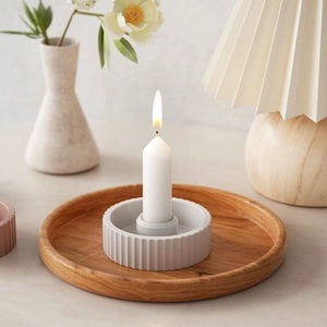 Detail of grey striped candle holder with white candle on a round wooden tray base