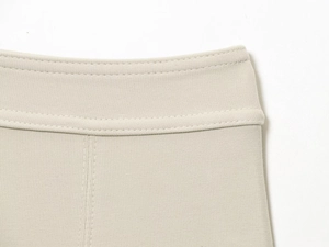 Detailed macro view of the stitching and knitted texture on the beige elastic waistline