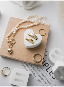 Macro shot of gold heart pendant pearl necklace and assorted rings on white props