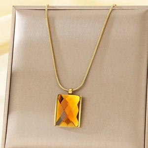 Macro shot of amber rectangular gemstone pendant on gold snake chain necklace