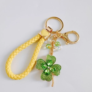 Detailed view of lucky four-leaf clover keychain with green rhinestones and yellow braided strap