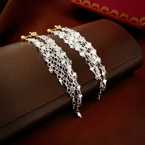 Macro detail of elegant gold and silver dual-tone long tassel chain drop earrings
