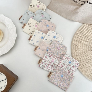 Floral fabric pouches with snap closures and woven labels on warm cream background