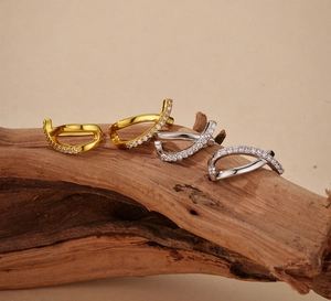 Macro detail of gold and silver crisscross stud earrings with pavé zircons on aged wood
